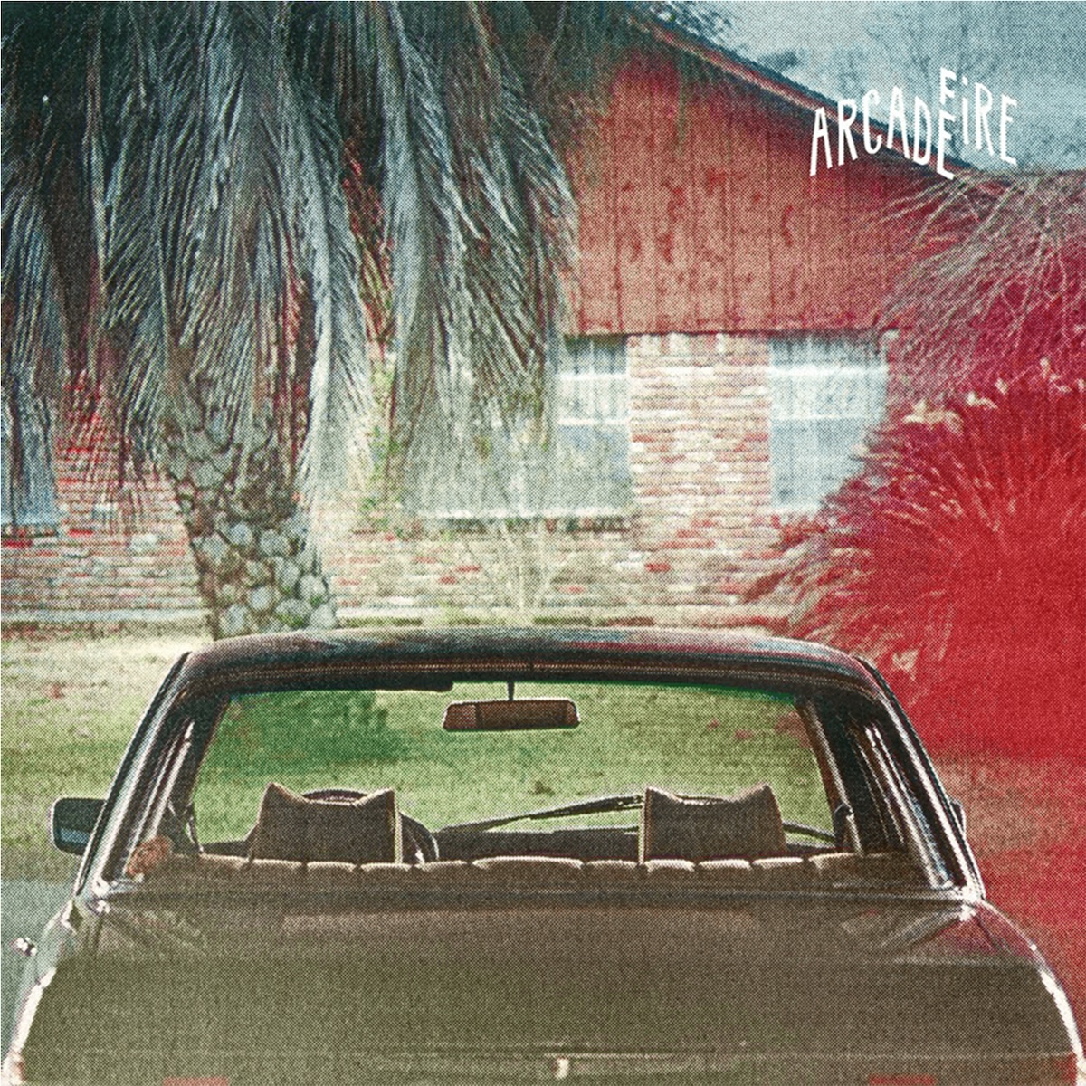 Album Art of Arcade Fire's The Suburbs album - In the foreground of this color photo, a grey/brown sedan is pictured from the back of the car, just above the license plate. The car is empty, and in front of the car and above it we can see a house with brick walls, windows, and a sided area under a sloped roof. There's a palm tree in front of the house on the left and a bush on the right, and the bush area has a red tint for some reason. There's a bit of grass on the ground, but also patches of dirt. In the top right, the band's name is written in white in all caps, with the 'F' of the second word behind the 'E' of the first word.