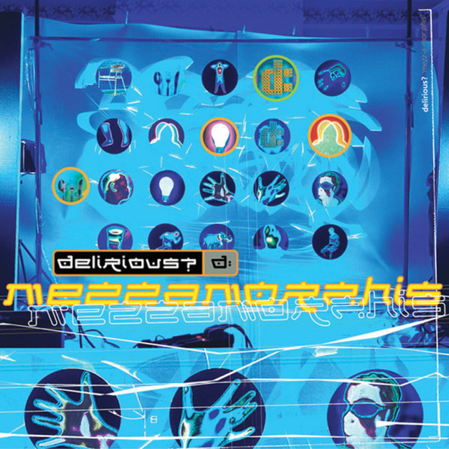 Album Art of delirious?'s Mezzamorphis album - Hung up on a canvas and surrounded by blue lights and lighting rig are some circles that look something like infrared hands, bodies, faces, lightbulbs, and more. In front of those is a black square with the band name ending in a question mark and then a gray box with a 'd:' in it. Then in yellow below it, the album title in yelllow with orange border. Rigging, power and lighting equipment are visible on the edges of the photo.