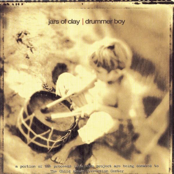 Album Art of Jars of Clay's Drummer Boy EP - A somewhat blurry black-and-white photo of a child of maybe 5 years old playing a small drum that is sitting in front of him on the ground. The drum looks pretty basic and handmade, maybe, and the whole image is tinted a golden yellow. Towards the top it has the band's name and the EP title 'Drummer Boy' on one line with a red vertical line between them. Around the edges, it seems to be a bunch of fake wear to the edges.