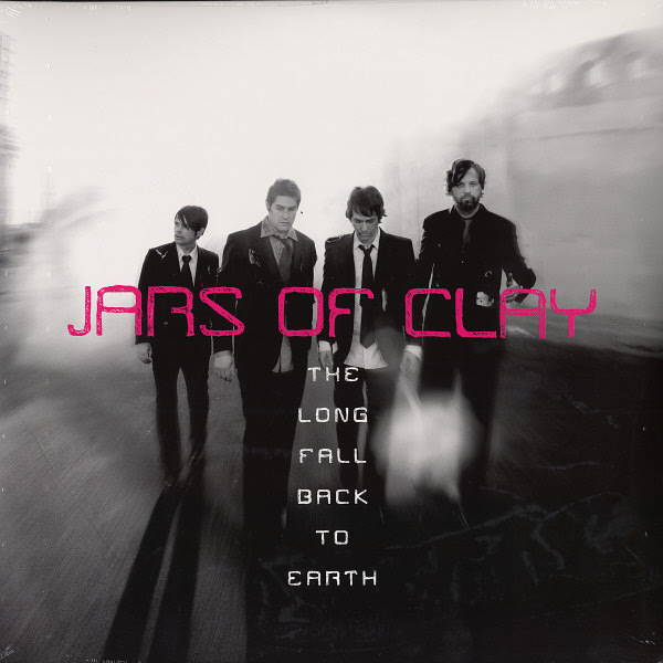 Album Art of Jars of Clay's The Long Fall Back To Earth album - A black-and-white photo of the four white men that make up the band, with the edges of the photo fairly hazy and/or smoky. All four members are wearing black suit coats and pants and most are not looking at the camera, maybe they are walking. The band's name is in large pink letters right over the photo in the center. The album title is down the middle of the bottom half, each word on its own line in smaller white letters.