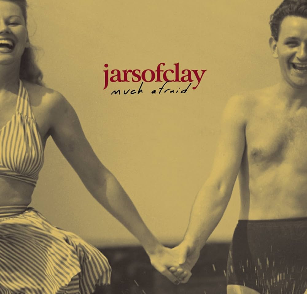 Album Art of Jars of Clay's Much Afraid album - On a golden background is printed the black-and-white photograph of a young man and woman in swimwear holding hands. From the framing of the photo, we only see one half of their bodies because the other half is cut off. It looks like they may be on a beach as there is some splashing water at the bottom.</body></html>