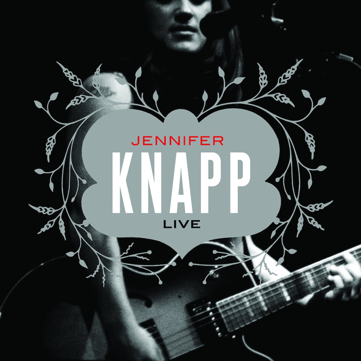 Album Art of Jennifer Knapp's Live album - A black and white photo of a woman in a dark room lit by some stage lights. Her face is right at the top in the middle, cut off at the eyes, and the bottom shows her holding an electric guitar while playing. She's also facing towards a microphone. In the center area, above the photo, is a gray, vaguely butterfly-shaped area that has 'Knapp' in big white letters, with 'Jennifer' in much smaller red letters above. And below her name is 'Live' in smaller black letters. Around the gray area is a symmetric plant design.