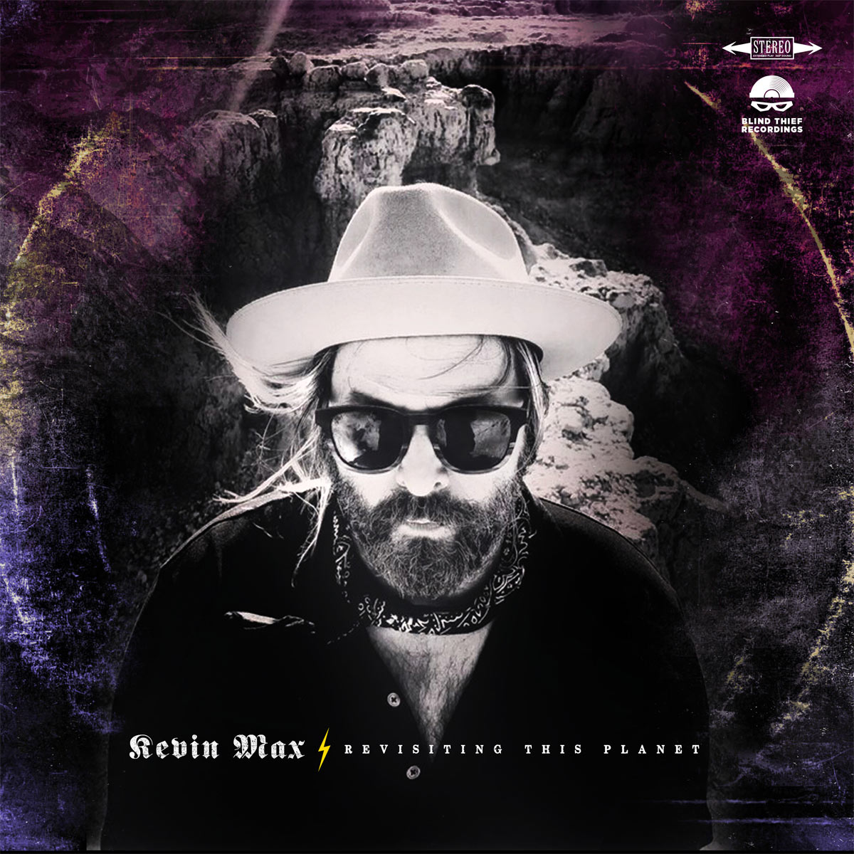 Album Art of Kevin Max's Revisiting This Planet album - A black and white photo of a white man in a trim beard wearing a black shirt and handkerchief around the neck is wearing sunglasses, a light-colored cowboy hat, and is standing on a rocky southern US landscape looking up at the camera. The cover has a purple hue on the edges and what looks like vinyl ringwear, where the record has been moved around so much that the case has been wearing out along the edges of the record. At the bottom is the artist name, a small yellow lightning bolt graphic, and the album name in smaller, white print.