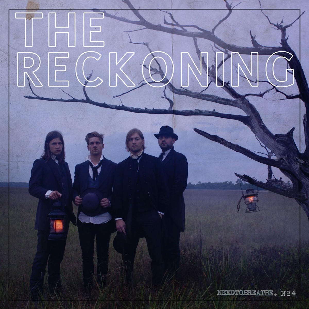 Album Art of Needtobreathe's The Reckoning album - On a hazy pre-dawn or post-sunset dusklight, a photo of four men standing in front of a field next to a bare tree's branches. Hanging on one of the branches and held by the left-most person are lanterns lit with a faint golden glow. All four men are wearing mostly black jackets and trousers, with white collared shirts visible underneath. They all look pretty serious in demeanor. At the top, printed in white outlined text over the blue-grey sky is the album title in huge letters, and in the bottom right corner in much smaller text it says 'Needtobreathe no. 4'. There's a thin black outline near the edges making a frame.