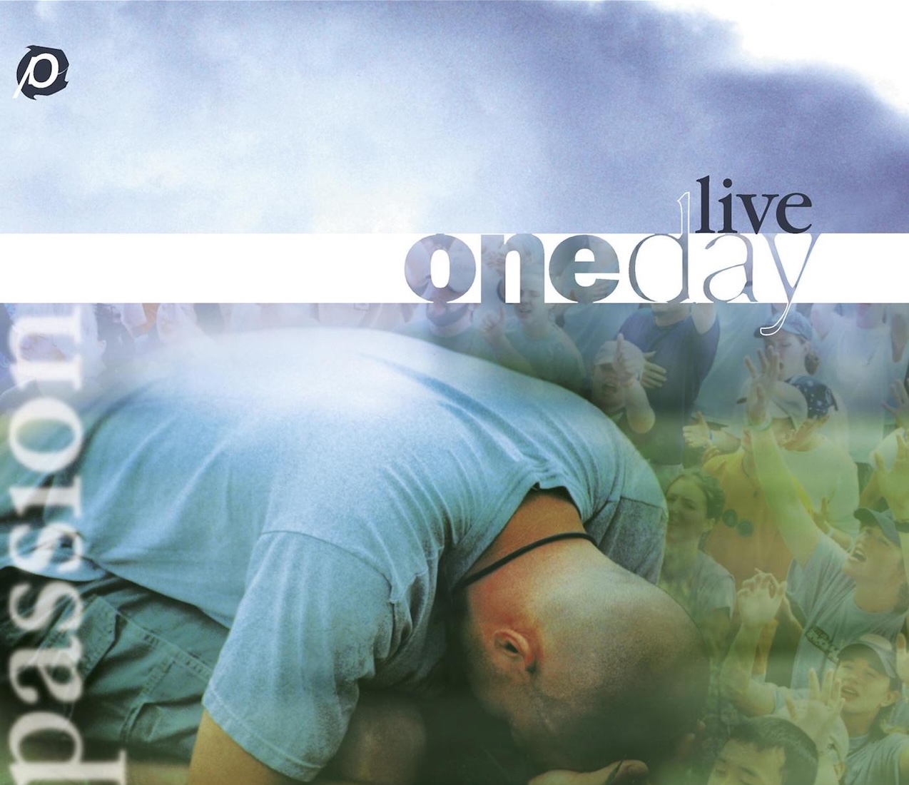 Album Art of Passion's OneDay Live album - A photo of a man kneeling on the ground with his head right at his knees and his head looking down into the ground, probably in prayer. Above him, the blue sky and next to him, layered in with the sky is a semi-transparent photo of dozens of people with their hands lifted in prayer and praise. On the left side, it has the word 'passion' in a semi-transparent, blurry white. In the top left, there's a 'p' wheel logo in white and black. Across the middle horizontally, it has a thick white line, and a series of holes in the white line is the words 'one' in bold and 'day' right after it much thinner. Above the line is printed 'live' in a thin black type.
