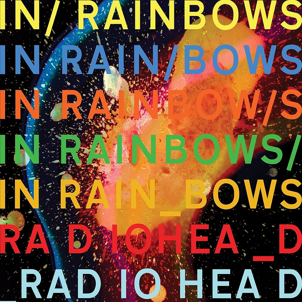 Album Art of Radiohead's In Rainbows album - 5 lines of text in large, colored letters that say 'In Rainbows' with random forward slashes or underscores inserted on occasion. Then two lines of 'Radiohead' with random spaces and underscores inserted. Behind that is some sort of bright orange ball with sparks emanating out of it and some lens flares on a black background.