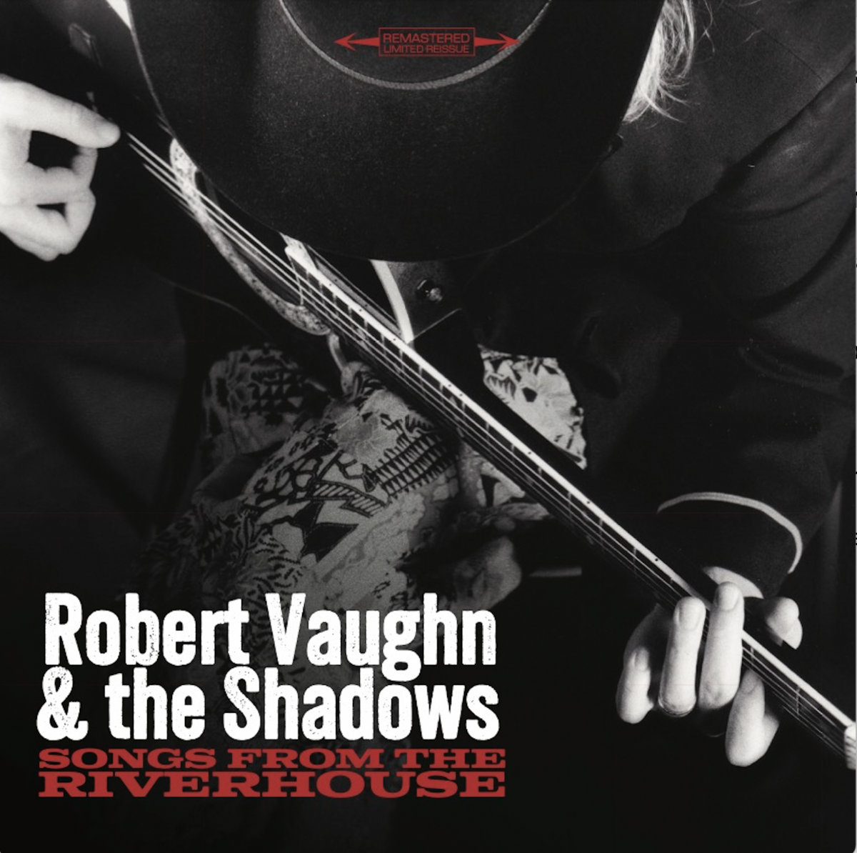Album Art of Robert Vaughn and The Shadows's Songs From The Riverhouse album - A black-and-white photo of a man in a black coat with a black cowboy hat on is pictured from above, showing his front and and the acoustic guitar he is holding and playing. Not much else is seen in the photo, except maybe some design of some cloth below the guitar. Printed in the bottom left corner is the band name and below it the album title in smaller red letters. In the top center, it has a red box that says 'Remastered Limited Reissue'.