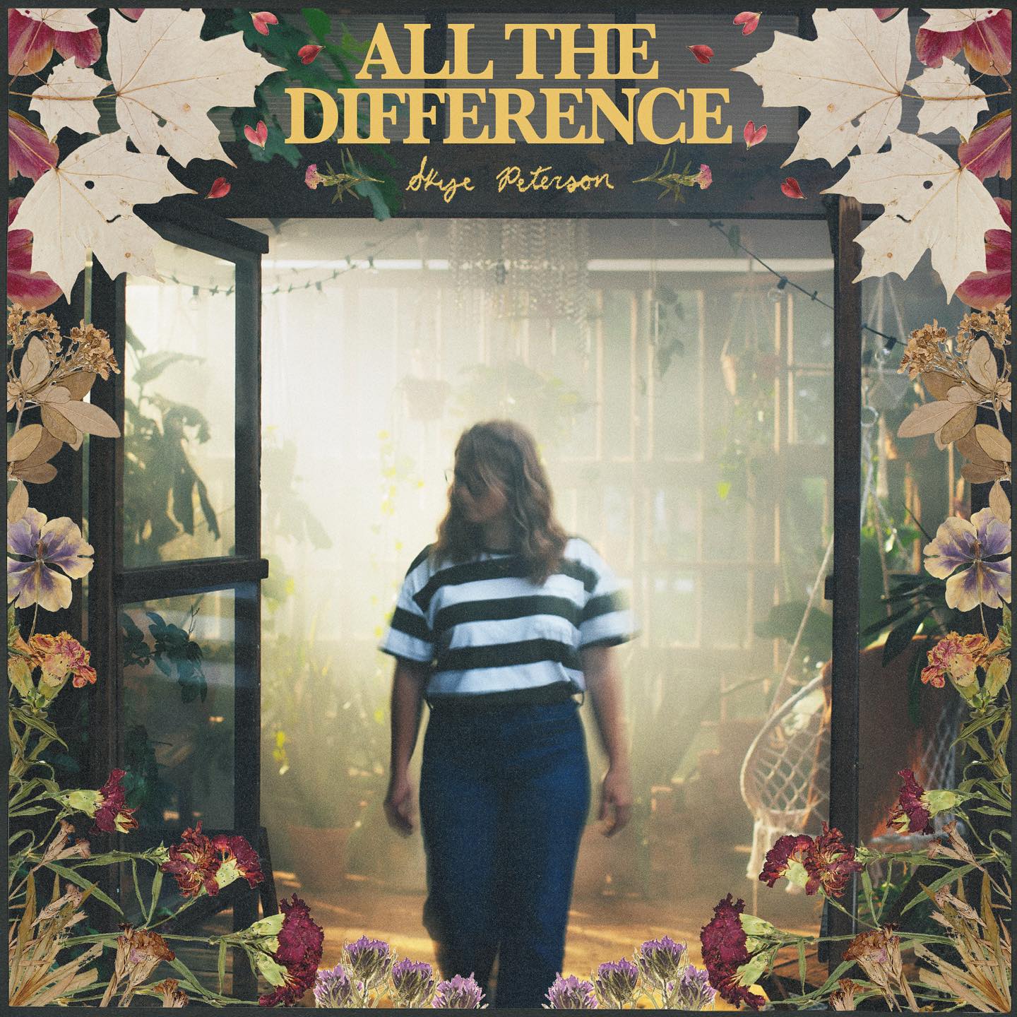 Album Art of Skye Peterson's All The Difference album - Standing in a doorway is a young woman with blue jeans, a black-and white shirt with large stripes, and should-length brown hair. Behind the doorway we can see the room is bathed in sunlight and has lots of plants. At the top, in yellow print, is the album title and Skye Peterson's name. The border of the cover is leaves and flowers of various colors.