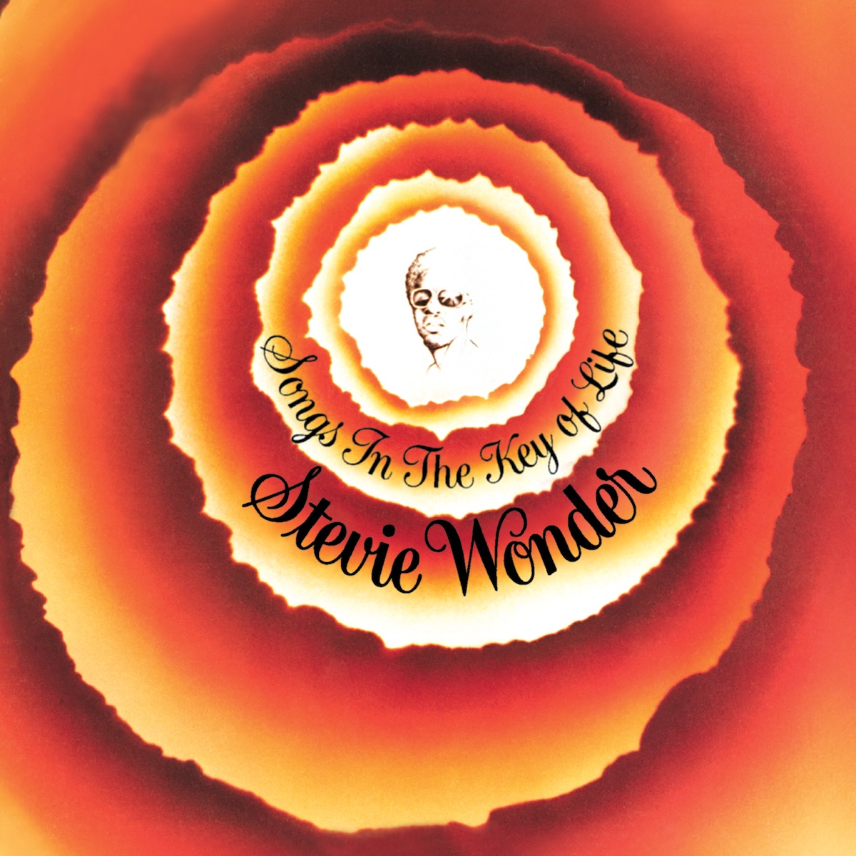 Album Art of Stevie Wonder's Songs In The Key Of Life album - A series of 5 circles are inside of each other, each circle with rough edges that seems ripped out of paper, maybe. The interior of the circles is darker than the outer edges, a dark red in the middle and more of a light gold on the outside, until you get to the innermost circles. The innermost, smallest circles is all white and has a drawing or black-and-white photo of a black man with curly hair from the shoulders up and wearing sunglasses. On a bottom part of the circles, printed in a fancy black cursive-style font, is the album title and below it in slightly bigger text, the artist's name.