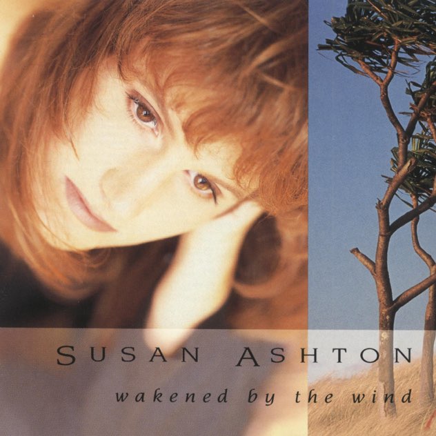 Album Art of Susan Ashton's Wakened By The Wind album - On the left four-fifths of the cover, a photo of a white woman with long brown hair and bangs is looking reflectively below the camera and everything but her face is out of focus. On the right fifth, a picture of a few lone trees in some tall, brown grass, with most of the low branches cut off and the top branches still with green leaves.</body></html>