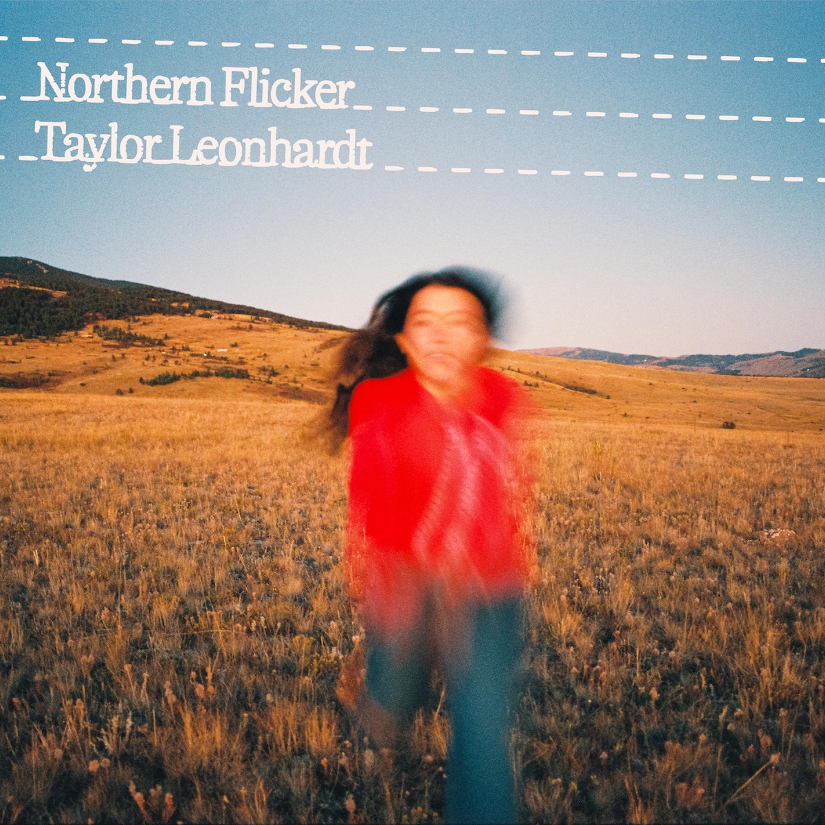 Album Art of Taylor Leonhardt's Northern Flicker album - A picture of a field with brown grasses and other small plants, which stretches in rolling hills into the background. In the left background, a hill rises and is covered in in trees towards the top, and in the right background, there are more hills visible much further away. In the foreground is a young womany with long, dark hair, a red top and blue jeans on. She's facing toward the camera but running towards it so that most of her is just a blur of color while the background is well in-focus. Up in the clear, blue-gray sky is printed above the photo three off-white, dashed lines from right to left, a bit lower on the right than the left. In the top left, on the 2nd and 3rd line, it has printed in the same color the album title and below it the artist's name.