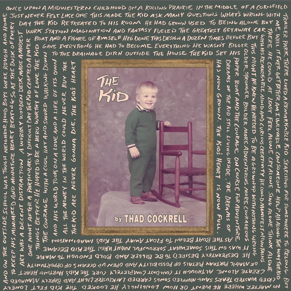 Album Art of Thad Cockrell's The Kid album - In the middle of the green background is an old photo in a golden frame of a kid, maye five years old, with an awed smile and a bright green onesie. He's standing next to a brown kids rocking chair and his left arm is on the top of it. He looks like he might be standing on a bed or some sort of platform against a mottled background. Above the top left of the picture it says 'The Kid' in a handwritten font, and at the bottom of the photo it says 'by Thad Cockrell'. Around the frame in the green background is a whole bunch of words, it seems like explaining the story of the kid, with the words at the top organized horizontally, but then the text starts going down the right side vertically. It continues to wrap inward around the photo on a large green background.