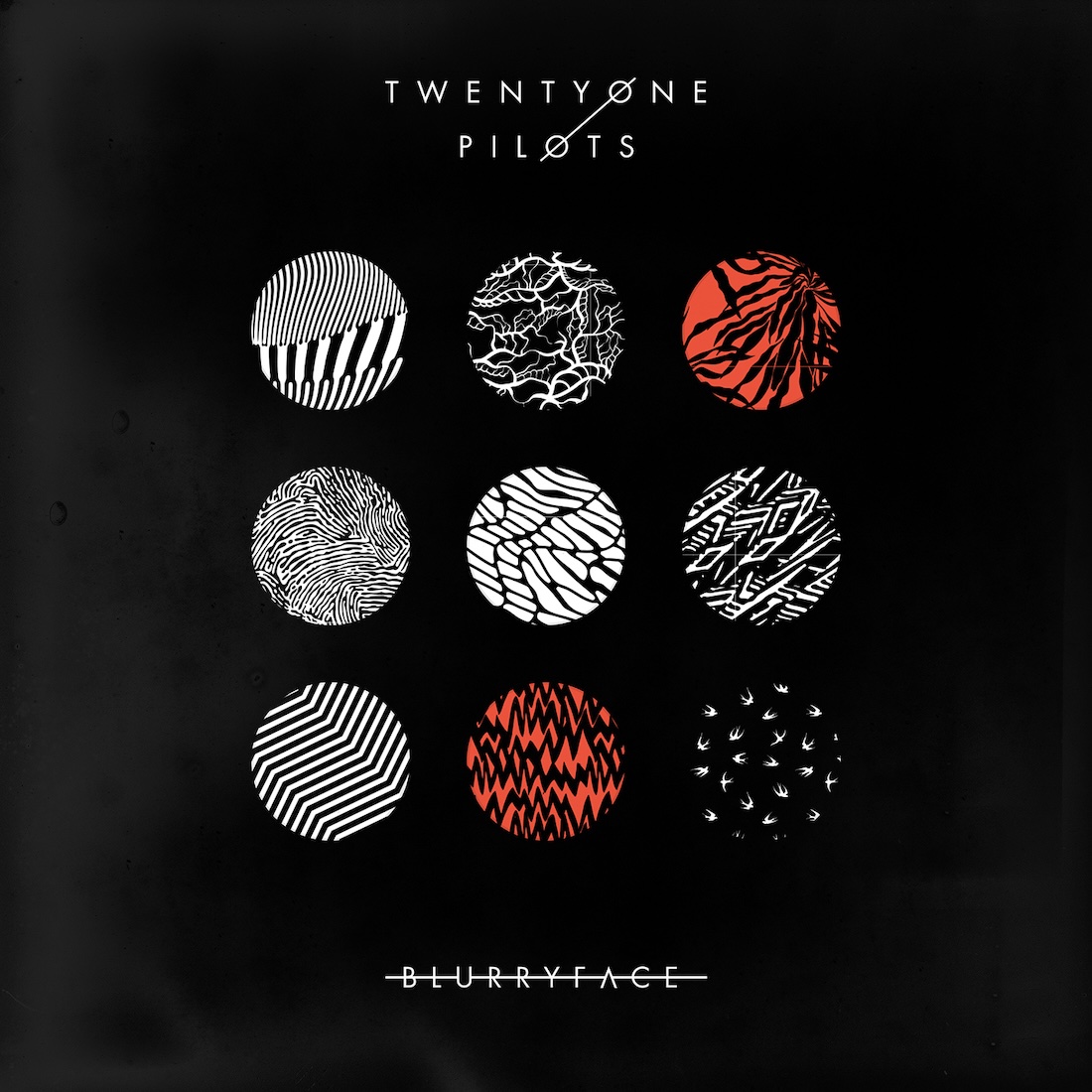 Album Art of Twenty One Pilots's Blurryface album - On a black background, there are 9 circles in the center. Each circle has a pattern inside it, mostly black-and-white, though two (top right and bottom center are red and black). Some are just geometric patterns, others look like plants or something. At the top, it says the band's name in white print on two lines, with the 'O' characters joined with lines between them. Below the circles is printed the album title with a strikethrough line, though the line goes behind the 'U' and 'A' characters.