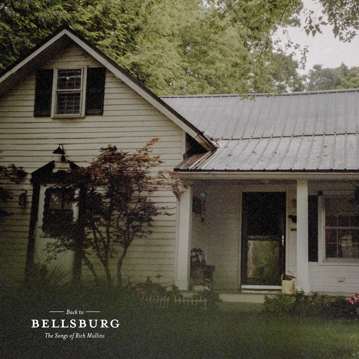 The Songs Of Rich Mullins album - A photograph of a simple, white house with a porch on the right side and a dormer on the left side. The photo fades to a dark green in the bottom and left and there it says in small text, 'back to' then `Bellsburg' in bigger, uppercase text. Below that it says 'The Songs of Rich Mullins'.